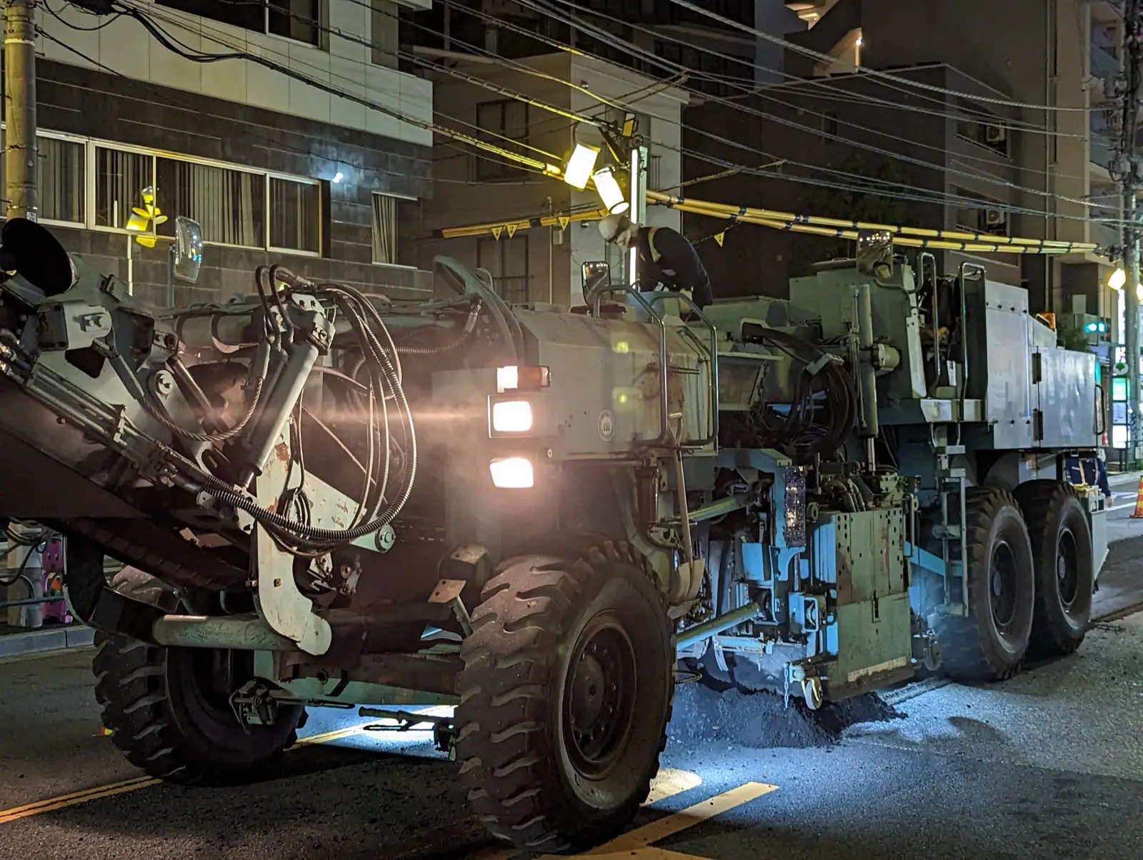 Asphalt milling machine grinding the top layer off a paved surface at night
