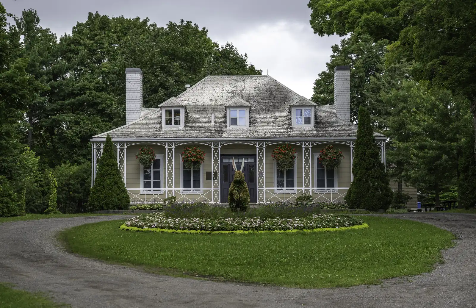 House with a full circle driveway looping around a planted lawn island in front of the porch