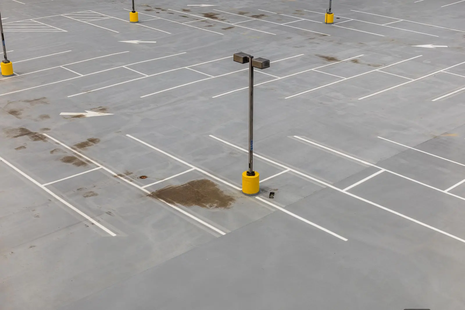 Aerial view of an empty parking lot with fresh white stall lines and directional arrows